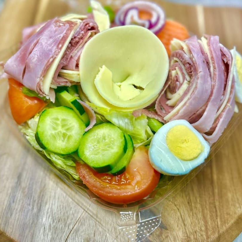 Fresh antipasto salad with ham, salami, cheese, lettuce, tomato, cucumber, onion, and egg.